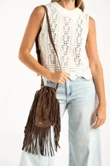 Top sin mangas de tejido de punto calado, color blanco, con cuello redondo acanalado y diseño de trenzas verticales. Presenta un ruedo con terminación festoneada.