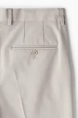Pantalón de vestir color beige, corte slim fit, con pliegues, bolsillos laterales y traseros ribeteados con botón.
