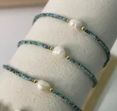 Pulsera de perla de río central y cuentas Miyuki en tonos celestes con detalles dorados.