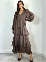 Vestido largo de seda italiana color chocolate, con escote en V, mangas largas abullonadas y diseño de falda con volados escalonados.