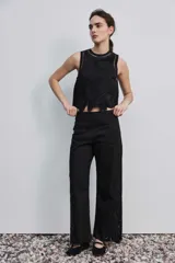 Pantalón negro de tiro alto y corte recto, confeccionado con detalles de bordados florales calados en la parte inferior de las piernas.