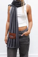 Bufanda tejida en técnica de jacquard con patrón de rayas verticales y parche en paño con bordado.