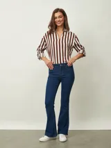 Jean de corte oxford con tiro medio, confeccionado en denim de color azul oscuro. Presenta un diseño ajustado en la parte superior y acampanado desde la rodilla hacia abajo, con cierre y botón frontal.