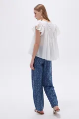Blusa de algodón blanca con cuello en V, frunces frontales y mangas cortas con volados.