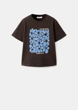 Camiseta marrón de algodón con cuello redondo y manga corta, con estampa frontal azul de flores y texto "Bloom More Worry Less".