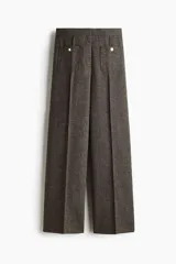 Pantalón de tiro alto en color marrón oscuro, con diseño de pierna recta y pliegues frontales cosidos. Presenta bolsillos de parche delanteros con botones decorativos dorados.