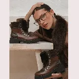 Borcego de cuero vacuno color marrón, de estilo montañés, con suela gruesa de goma, cordones con ganchos metálicos y detalle de corderito en la lengüeta.