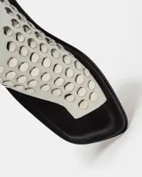 Sandalias planas blancas de cuero, con tira ancha sobre el empeine adornada con tachas plateadas.