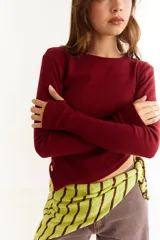 Top de manga larga color blanco, confeccionado en tejido de punto acanalado con diseño irregular y aberturas para los pulgares en los puños.