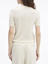 Sweater de lana merino color crema, de corte slim, cuello perkins y manga corta. Presenta detalles de puntadas en los hombros y ribetes de canalé en cuello, puños y bajo.