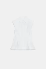 Camisa sin mangas de algodón blanco, con cuello solapa, pliegues en la cintura y bajo evasé. Cuenta con cierre frontal con botones ocultos.