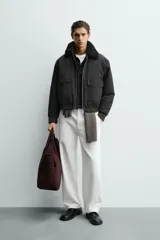 Cazadora bomber de corte cropped confeccionada en algodón, color negro. Presenta cuello de solapa con efecto borreguillo a contraste, cierre frontal con cremallera metálica, bolsillos delanteros tipo plastrón con solapa y acabados en rib en puños y bajo.