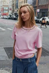 Remera de algodón color rosado, con cuello redondo decorado con una aplicación de joyas y pedrería, manga corta y corte regular.
