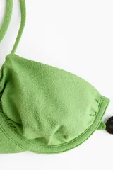 Top de bikini con aros color verde, con tirantes ajustables y cuenta decorativa en el centro.
