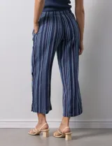 Pantalón de algodón estampado a rayas verticales azules y blancas, marca Erika. Tiene pretina elastizada, bolsillos delanteros, ruedo lateral con tajo y botones decorativos.