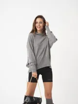 Sweater gris de tejido fino con cuello alto, silueta amplia y hombro caído.