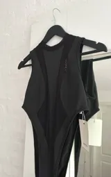 Body negro con cuello redondo, sin mangas y corte cavado. Presenta paneles de tela opaca en el centro y laterales, y paneles de tela transparente en el frente y laterales.