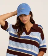 Gorra de sarga celeste con ala curva y bordado frontal con la inscripción "Sol & Mar" en color amarillo. Cuenta con ajuste en la parte posterior.