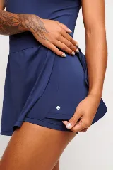 Vestido deportivo negro sin mangas, con escote en V y logo estampado en el pecho. Falda corta con short interno y bolsillos laterales. Incluye protección UV50+.