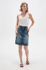 Falda de jean estilo clásico con bolsillos frontales y traseros, tiro alto y lavado azul medio con efecto desgastado.