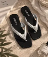 Sandalias tipo ojota de base negra con punta cuadrada y tiras acolchadas en color plateado.
