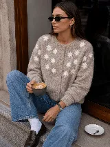 Cardigan de punto color blanco marfil, con cuello redondo, manga larga y cierre frontal de botones forrados. Presenta delicadas flores bordadas en relieve a lo largo del frente y las mangas.
