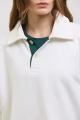 Buzo de algodón con diseño bicolor en blanco y verde inglés, cuello tipo chomba con botones frontales, mangas largas con puños y corte holgado a la cintura.