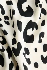 Top entallado de punto con estampado de leopardo, escote asimétrico amplio y un hombro al descubierto. Modelo de manga larga con frunces en el escote para crear un efecto drapeado.