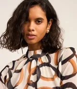 Blusa de mangas largas de chiffon, con cuello alto y cierre por gota. Estampa de eslabones entrelazados con detalles de pequeños corazones.