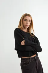 Sweater de punto negro, de corte holgado y diseño cropped, con cuello redondo y mangas largas.