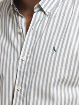 Camisa de manga larga con corte slim fit, confeccionada en algodón con diseño de rayas verticales en tonos blanco y azul. Presenta cuello con botones y logo bordado en el pecho.
