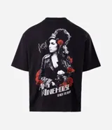 Remera boxy fit de algodón color negro, con cuello redondo y mangas cortas. Presenta un estampado de la cantante Amy Winehouse en blanco y negro con detalles en rojo, y la inscripción "Amy Winehouse Back to Black".