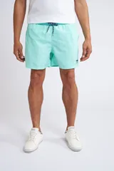 Short de baño color turquesa con cintura elástica y cordón ajustable. Presenta bolsillos laterales y un bolsillo trasero, con el logo de la marca bordado en la parte inferior de la pierna.