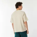 Camiseta beige de manga corta raglán con estampado frontal con el texto "[NXT-K] NO LIMITS, NO HESITATIONS".