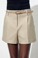 Bermuda color crema de tiro medio con pinzas delanteras y cinturón fino color beige. Tiene bolsillos frontales y falsos bolsillos de vivo en la espalda. Cierre frontal con cremallera, botón interior y gancho.