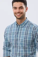 Camisa de manga larga de calce slim, con diseño a cuadros en tonos azul oscuro, verde y blanco. Presenta cuello camisero con botones y bolsillo ojal en el pecho con detalle bordado.