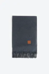 Pashmina de textura suave en color azul, con terminación de flecos en los extremos y un pequeño aplique de cuero sintético con logo grabado.