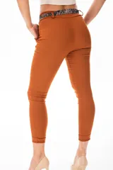 Pantalón de vestir color terracota, de corte ajustado, con cintura plisada, bolsillos laterales y cinturón estampado con lazo.