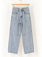 Pantalón de jean estilo barrel fit en color azul claro, con tiro alto, bolsillos delanteros y traseros, y costuras decorativas a la altura de las rodillas con aberturas en el bajo.