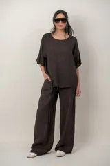 Blusa de lino color marrón oscuro, con escote redondo, mangas cortas amplias y detalle de alforzas verticales en el lateral derecho.