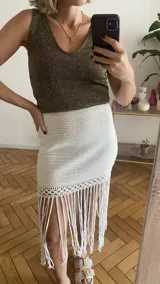 Falda tejida a mano en crochet, color crudo, con flecos en el ruedo y abertura lateral.