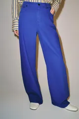 Jeans de tiro medio y corte barrel leg, de color azul, con diseño de cinco bolsillos y trabillas en la cintura. Cierre frontal con cremallera y botón metálico.