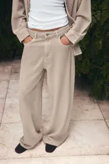 Jeans de tiro alto con diseño de pierna ancha y cinco bolsillos. Cuenta con cierre frontal mediante cremallera y botón metálico.