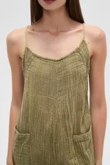 Mono de algodón color verde oliva, con textura plisada, escote en V y tirantes finos tipo lencero. Presenta bolsillos frontales y corte holgado.