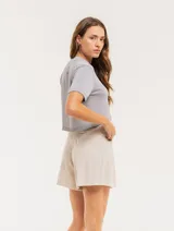 Short color beige de lino con tiro alto, elástico en la pretina trasera, cierre delantero con botón, tablas en el frente, bolsillos delanteros y dobladillo invisible.