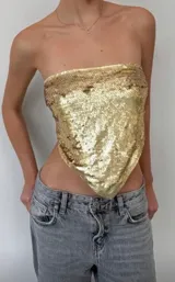 Top strapless de lentejuelas doradas con diseño tipo bandana y terminación en punta en el frente.
