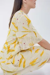 Vestido corto acampanado color crema con estampado de hojas amarillas, cuello redondo y mangas cortas.