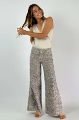 Pantalón jean de corte ancho con estampado animal print en tonos beige y gris.