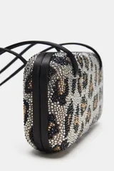Bolso de hombro formato caja con estampado animal print cubierto de apliques brillantes. Posee doble asa de hombro, bolsillo interior y cierre imantado.