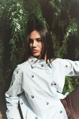 Camisa de algodón de corte holgado, color celeste claro con bordados de flores pequeñas en toda la prenda. Presenta cuello clásico, cierre frontal con botones y mangas largas.